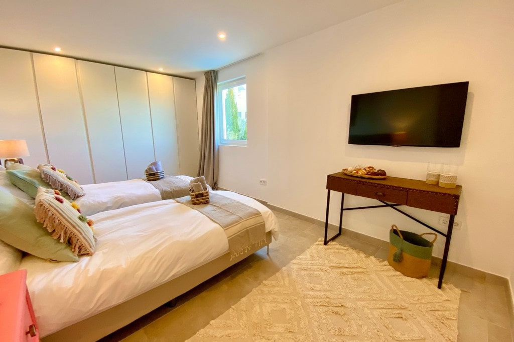room 3 features 2 x single beds, smart TV, fitted wardrobes and air conditioning. The large bathroom offers a freestanding bath, twin sinks, rain shower & WC.